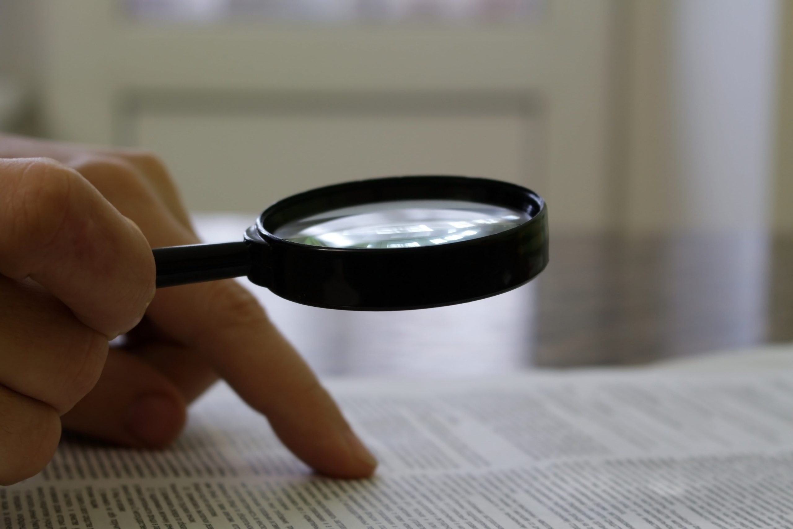 Hands Reading Papers with Magnifying Glass